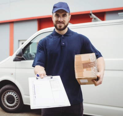 Delivery man holding a package and clipboard in front of a white van, smiling.