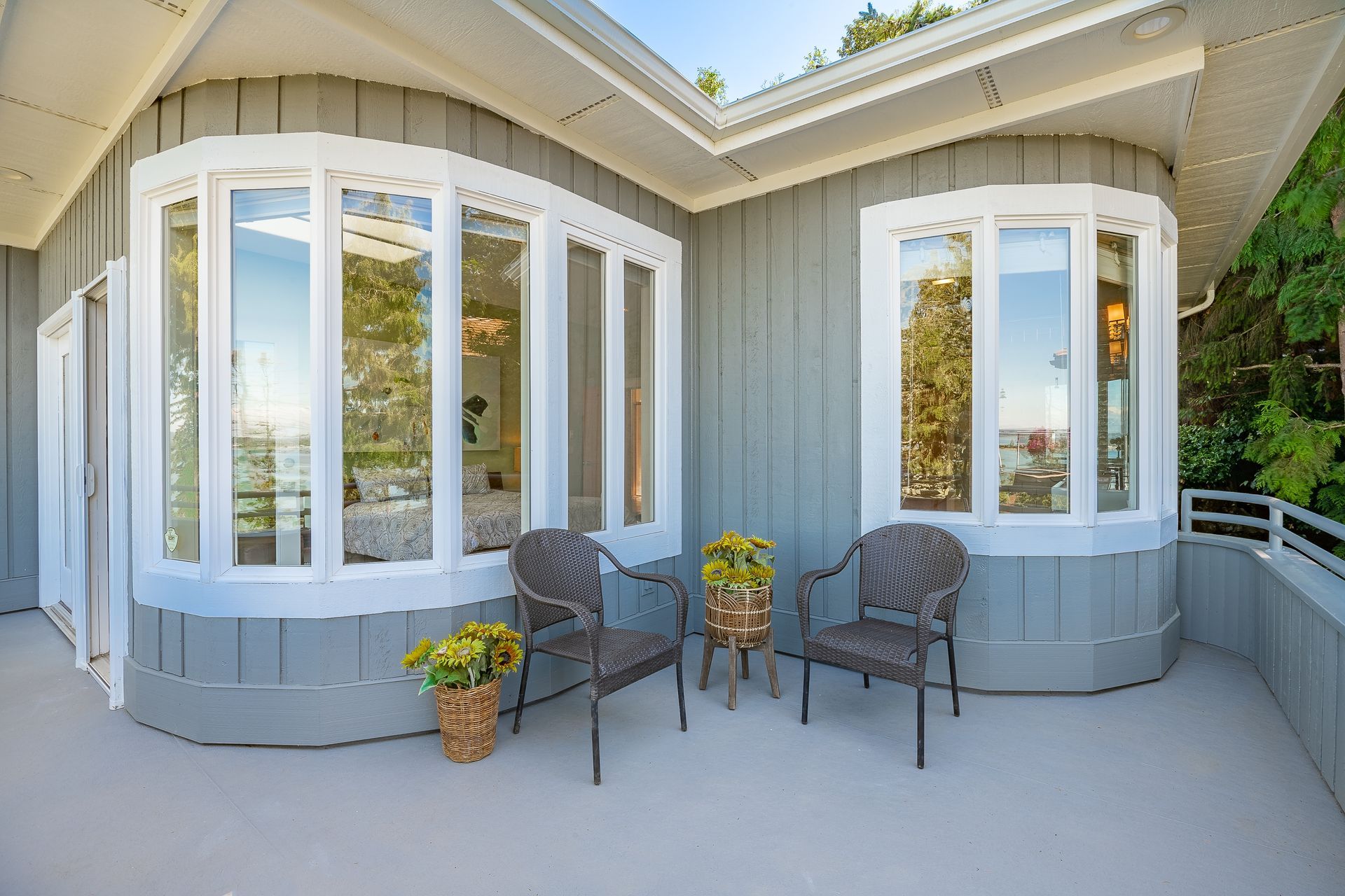 There are two chairs and a table on the balcony of a house.