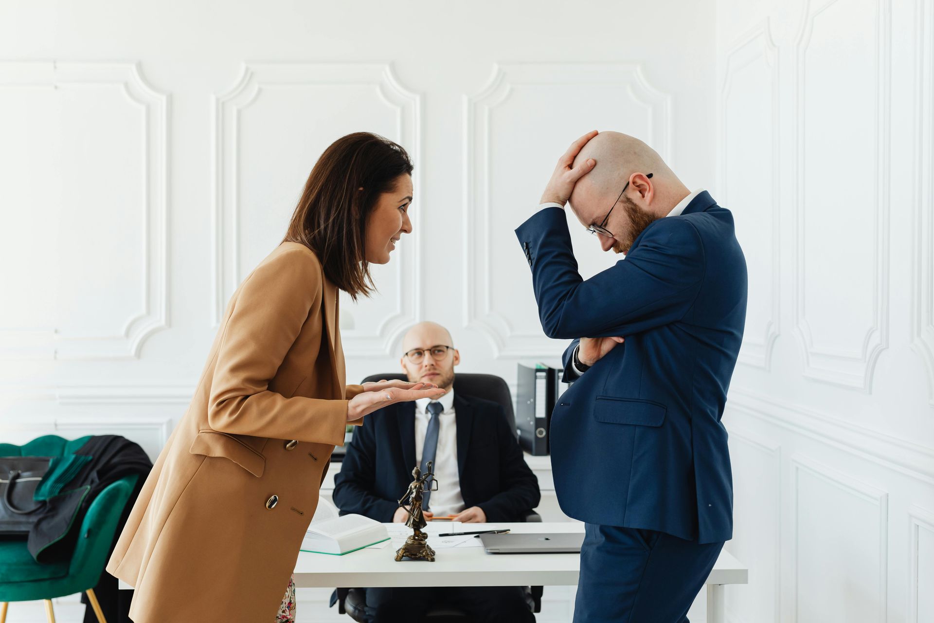 Woman arguing with man, mediator at desk in white office.