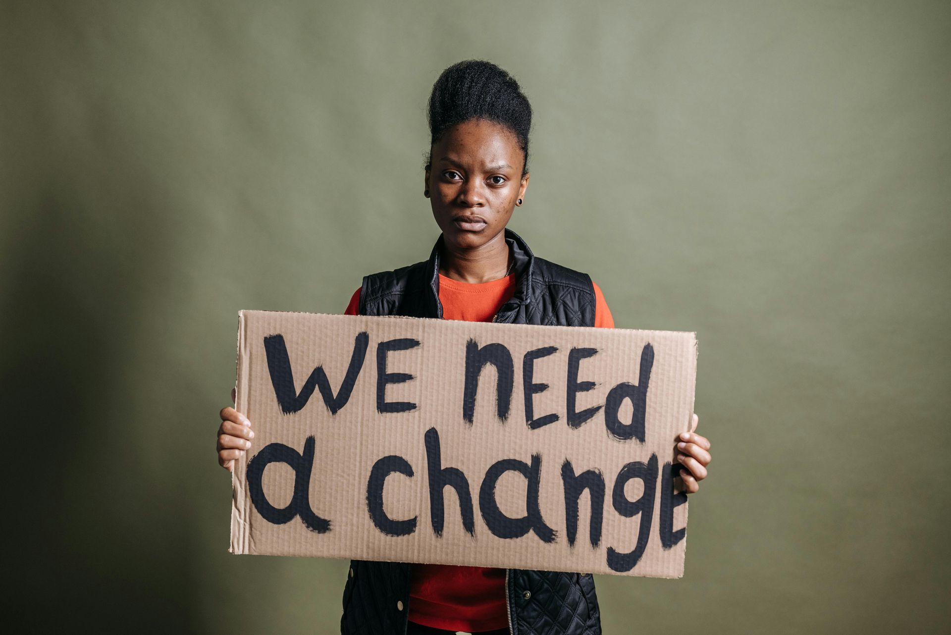 Woman holding a cardboard sign that reads 