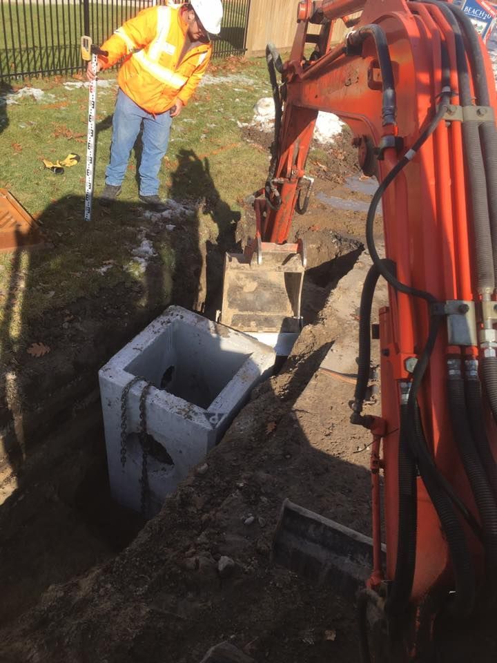 A man in a hard hat is standing next to an orange excavator