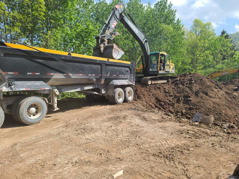 A dump truck is being loaded with dirt by an excavator.