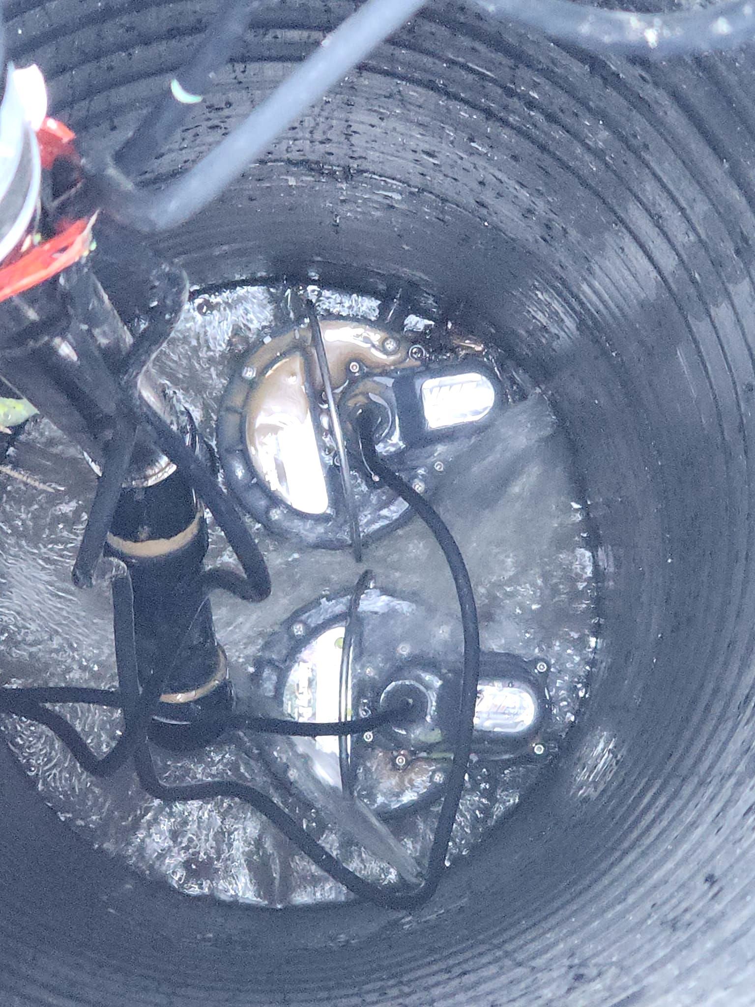 A man is cleaning a drain with a vacuum cleaner.