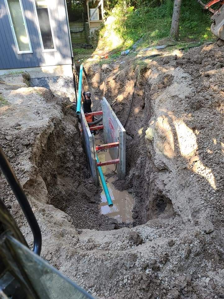 A man is digging a hole in the ground next to a house.