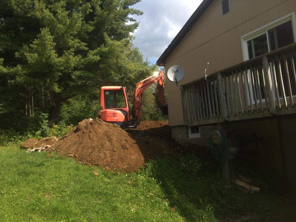 An excavator is digging a hole in front of a house.
