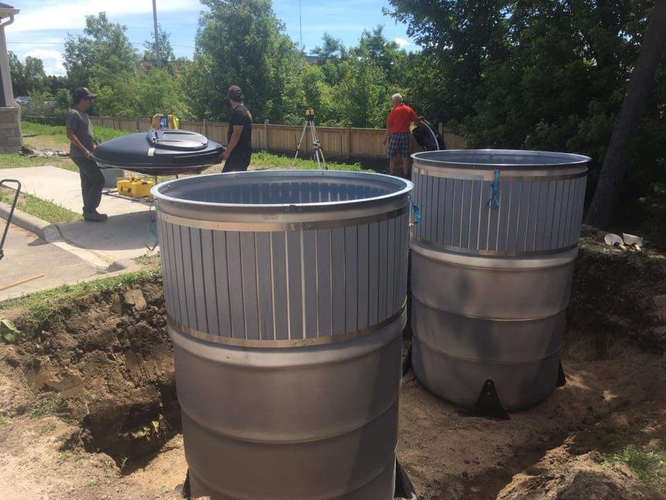 A couple of barrels are sitting in the dirt next to each other.