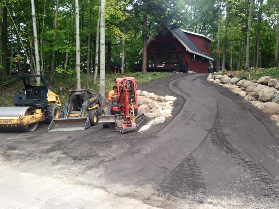 A red house is behind a row of construction vehicles