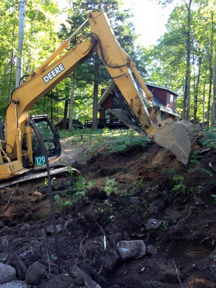 A yellow deere excavator is digging a hole in the dirt
