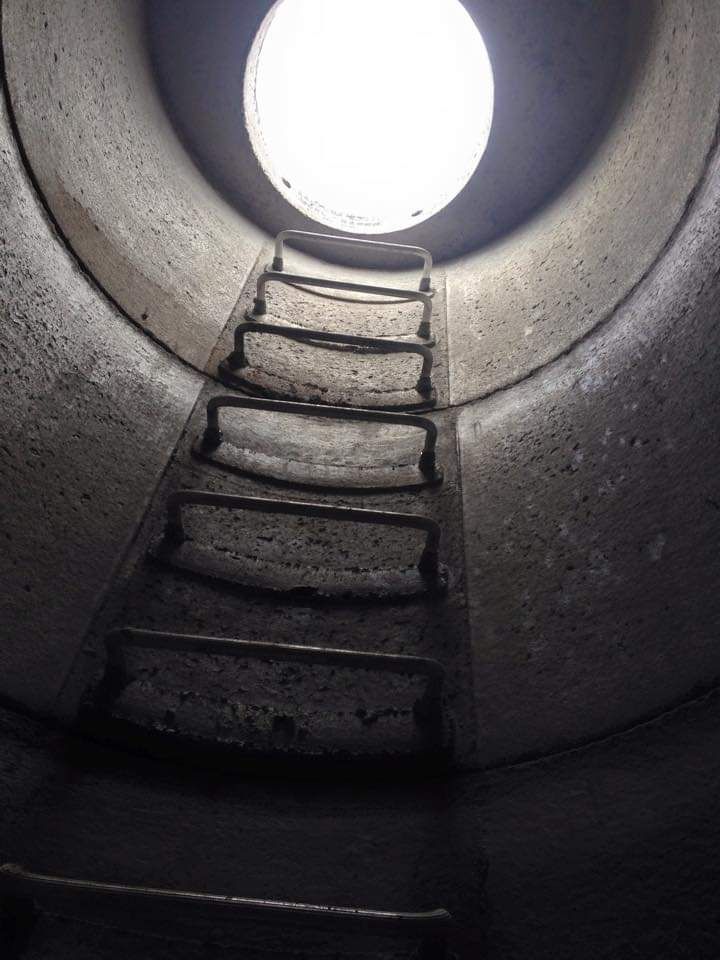 A staircase leading up to a light at the end of a tunnel.