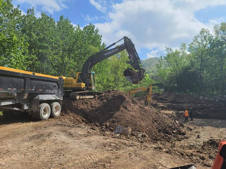 A volvo excavator is loading dirt into a dump truck.