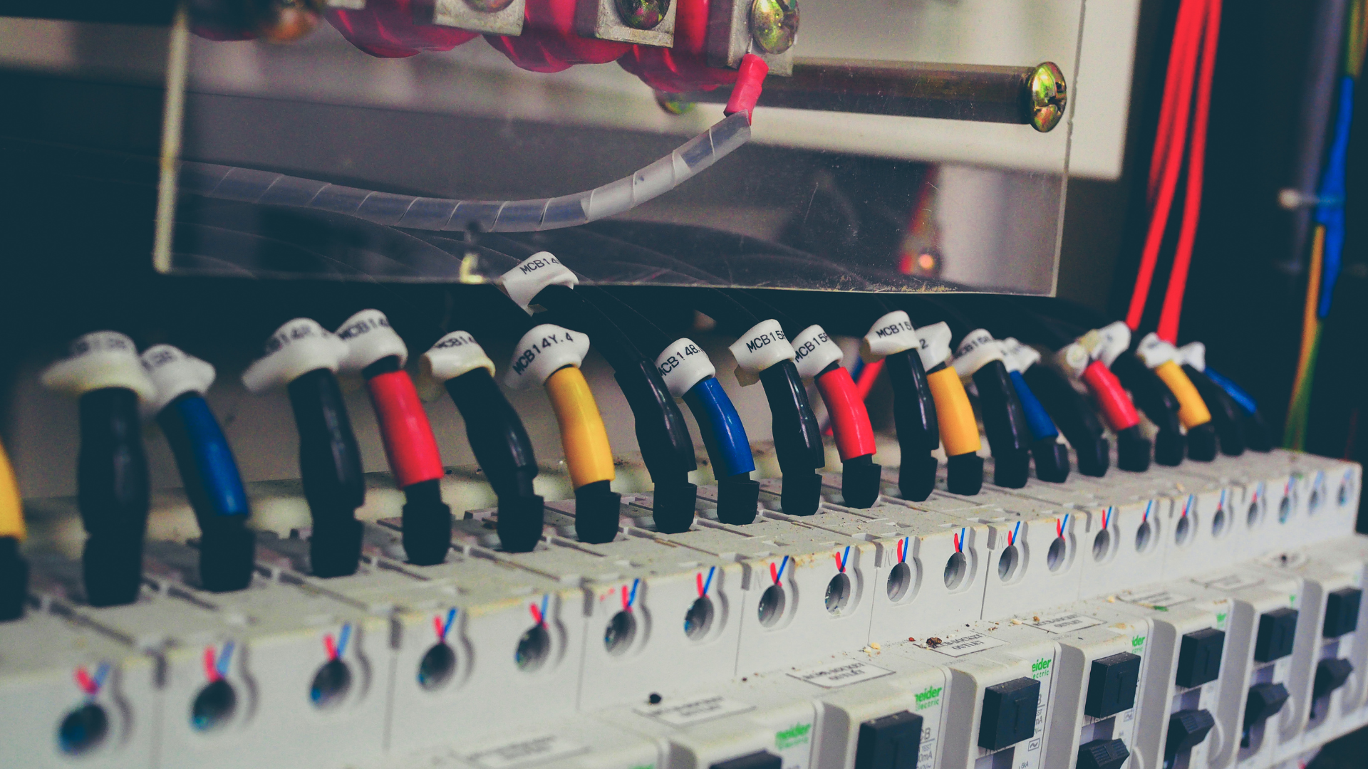 Electrical panel with rows of circuit breakers and multicolored wires connected.