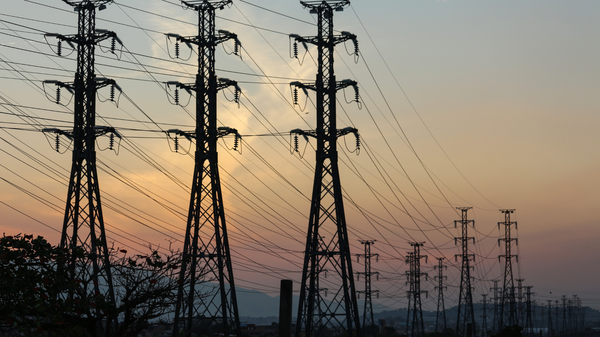 Power lines stretch across a dusky orange sky.