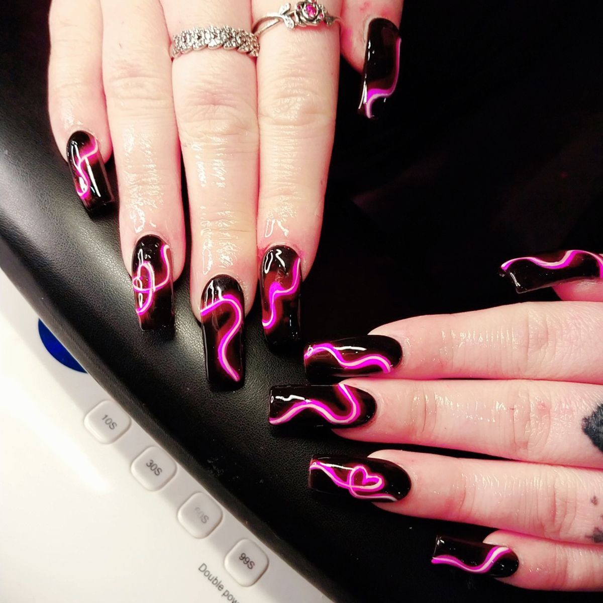 Hard gel nail extensions with glow in the dark pink neon swirls on black