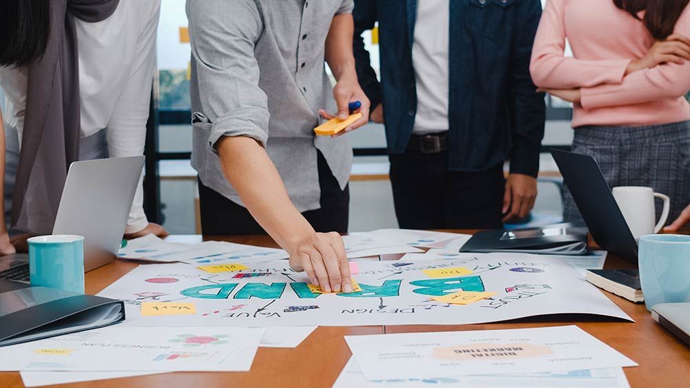 A group of people are standing around a table with sticky notes on it.