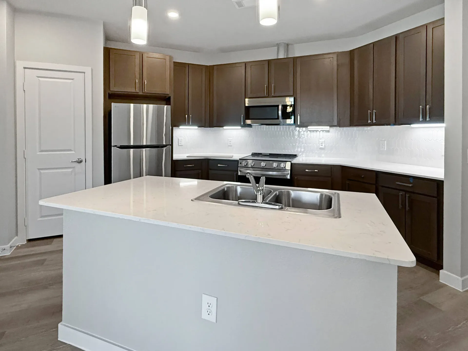 Modern kitchen with island, stainless steel appliances, and dark wood cabinets.