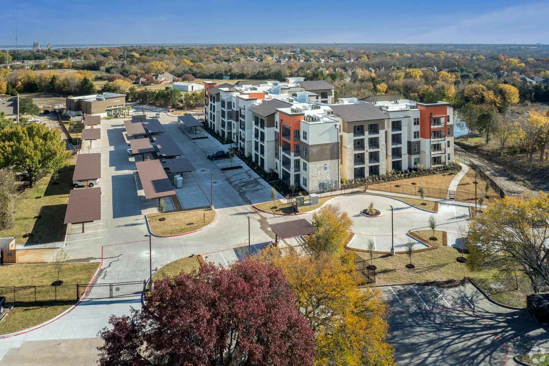 Aerial view of a multi-story apartment building with covered parking and landscaping.