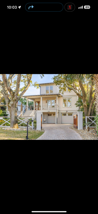 Two-story house with gray facade, two garage doors, and front porch. A tree on each side of the house.