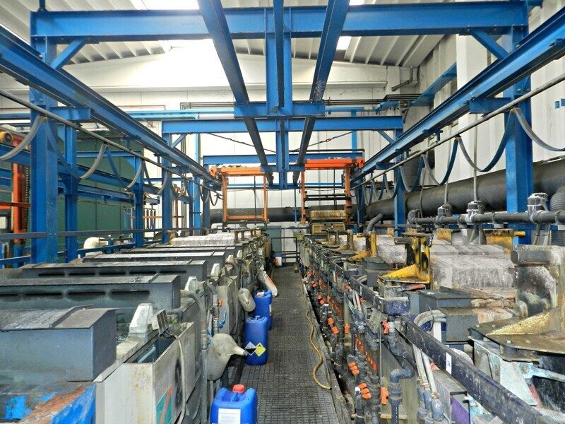 Interno di una fabbrica industriale con travi in ​​acciaio blu, macchinari, tubi e attrezzature disposti in file