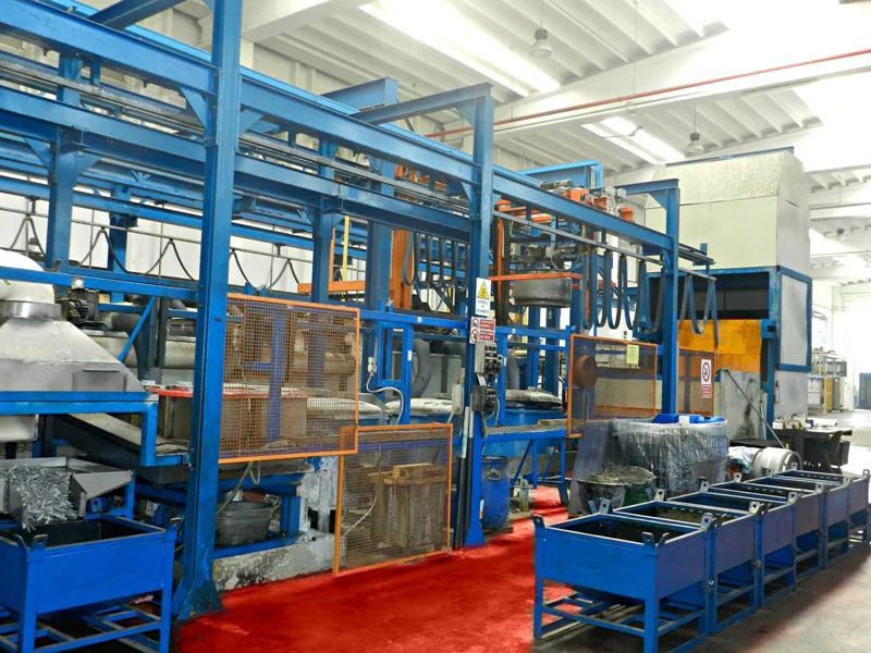 Stabilimento industriale con macchinari blu, scaffalature metalliche e pavimento rosso in un luminoso capannone di produzione.