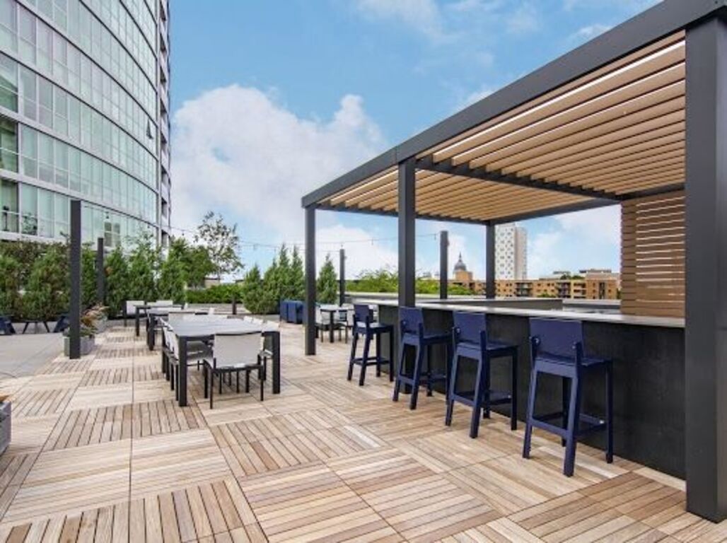 A rooftop deck with tables and chairs and a pergola at  LMP Apartments in MO.