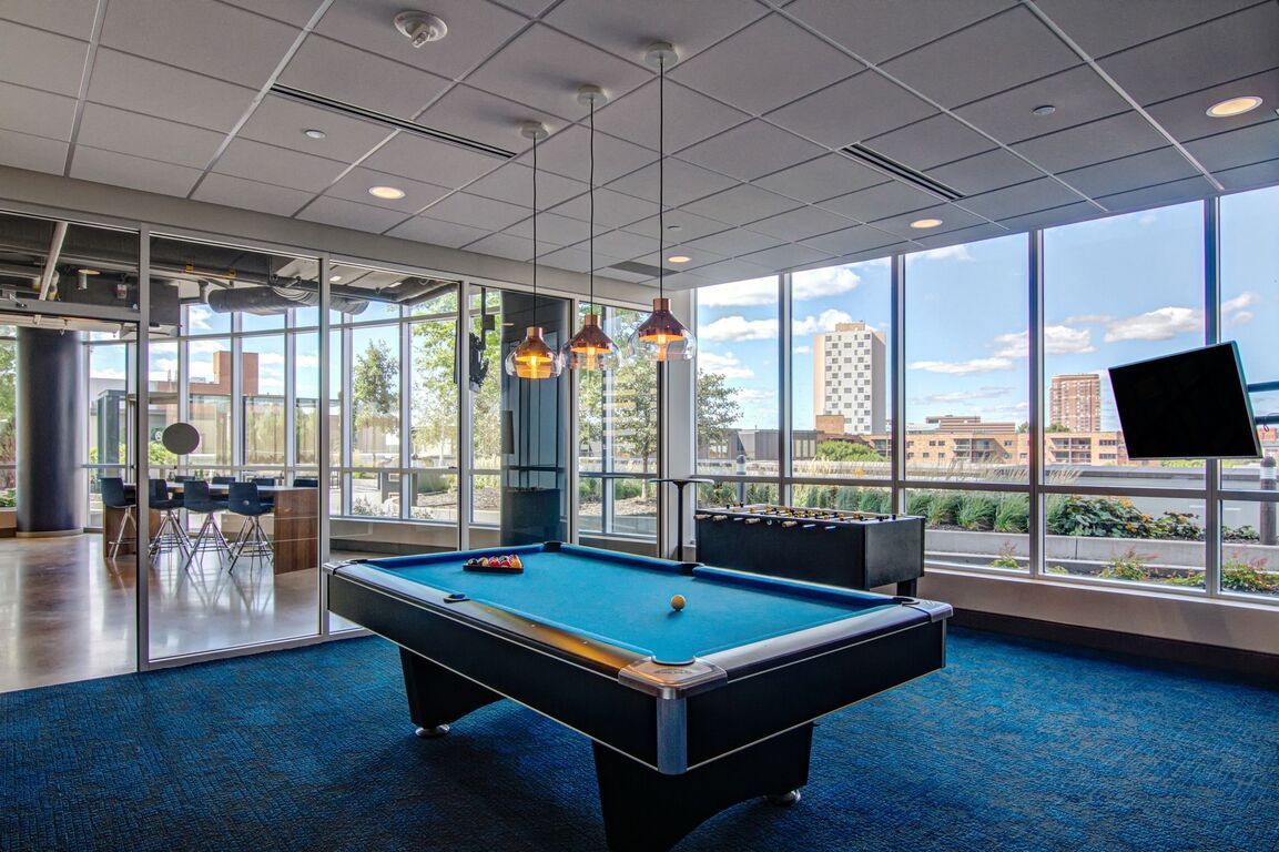 A pool table in a room with a lot of windows at  LMP Apartments in MO.