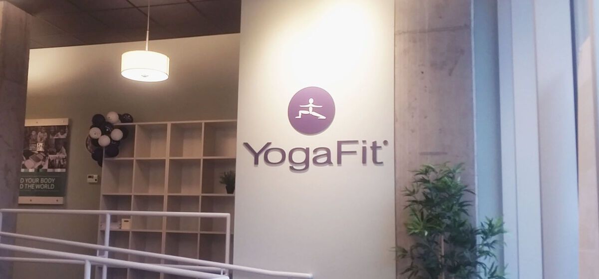A yoga fit sign is on the side of a building.