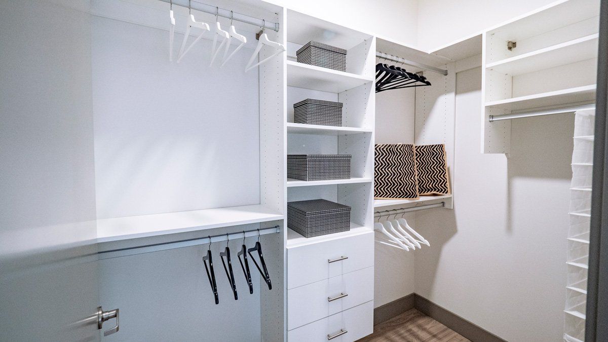 A walk in closet with a lot of shelves and clothes hanging on the racks.