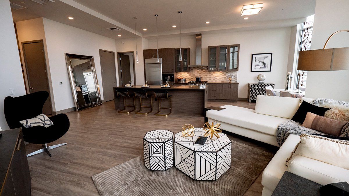 A living room with a couch , chair , coffee table and kitchen.