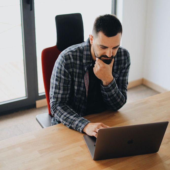 A man in a plaid shirt using a laptop.