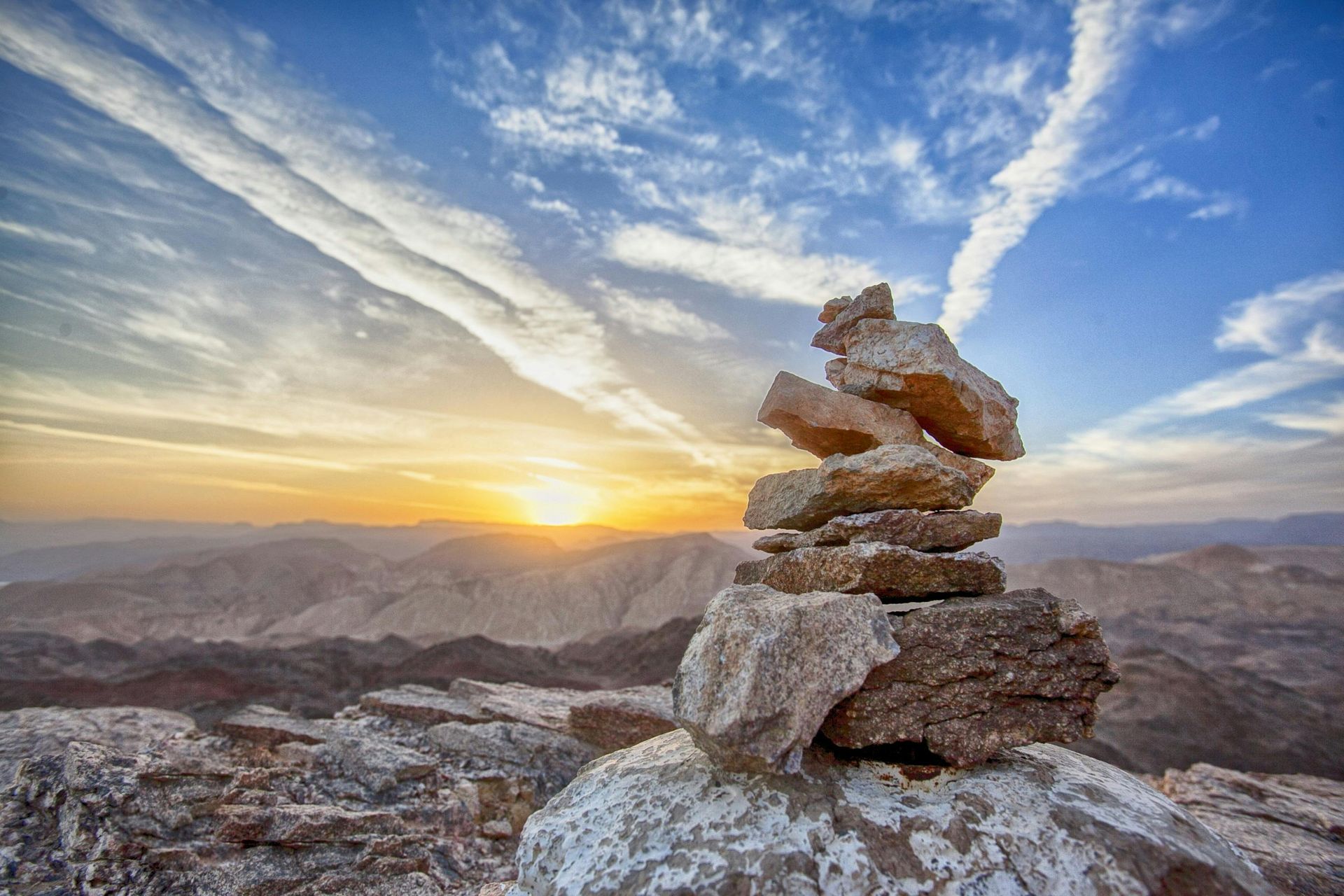 A pile of rocks on top of a mountain at sunset.