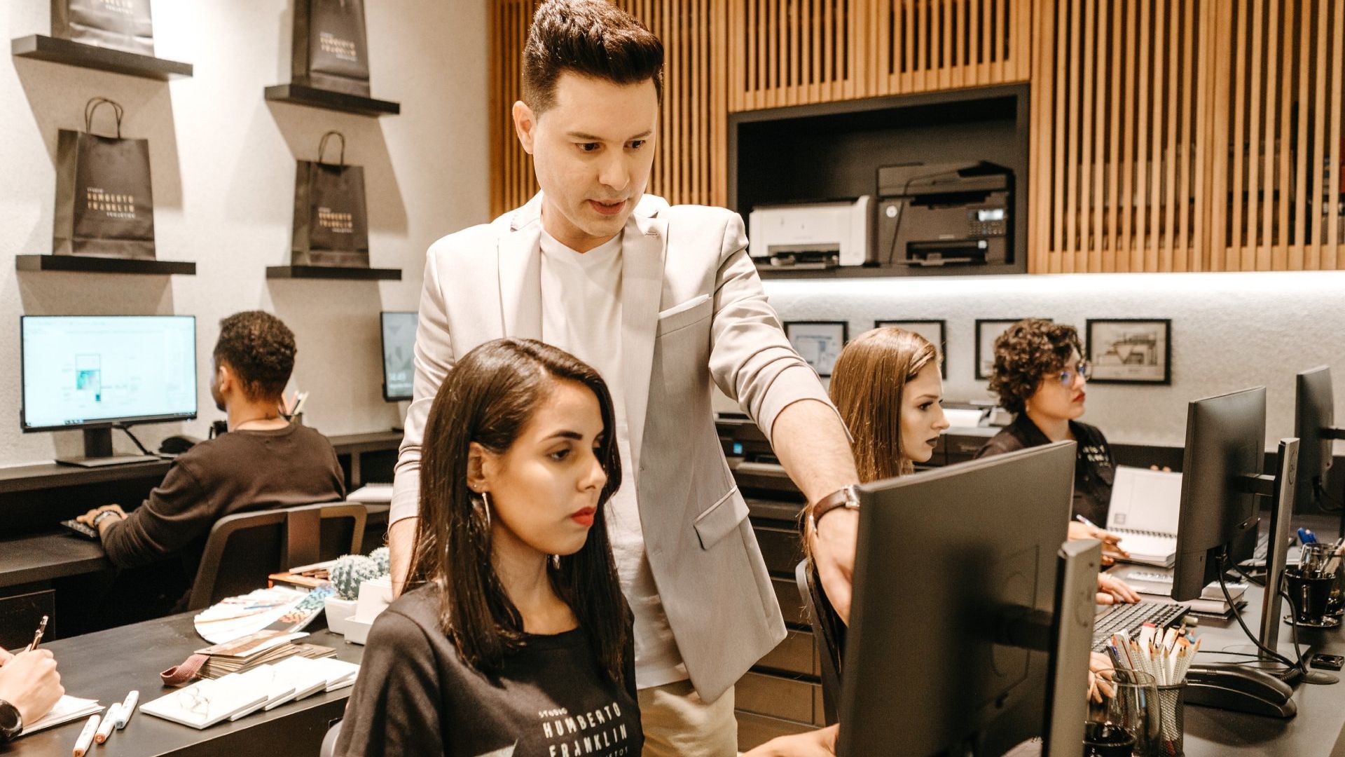 A man is standing next to a woman looking at a computer screen.