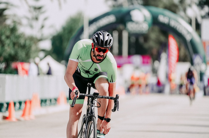 Man in a triathlon getting on a bicycle