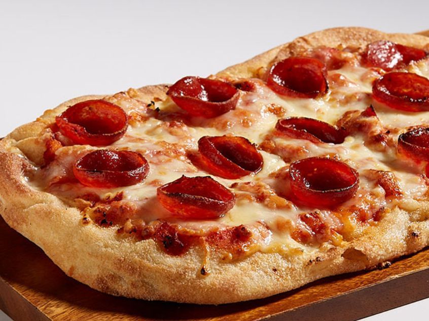 A pepperoni pizza is sitting on a wooden cutting board