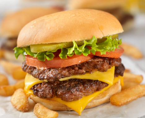 A double cheeseburger with lettuce , tomato , pickles and french fries on a bun.