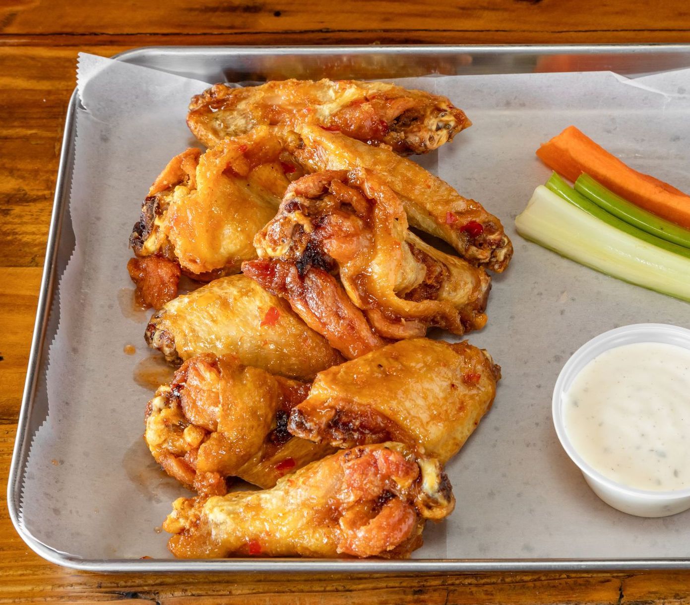 A tray of chicken wings with celery and carrots and a side of ranch dressing.