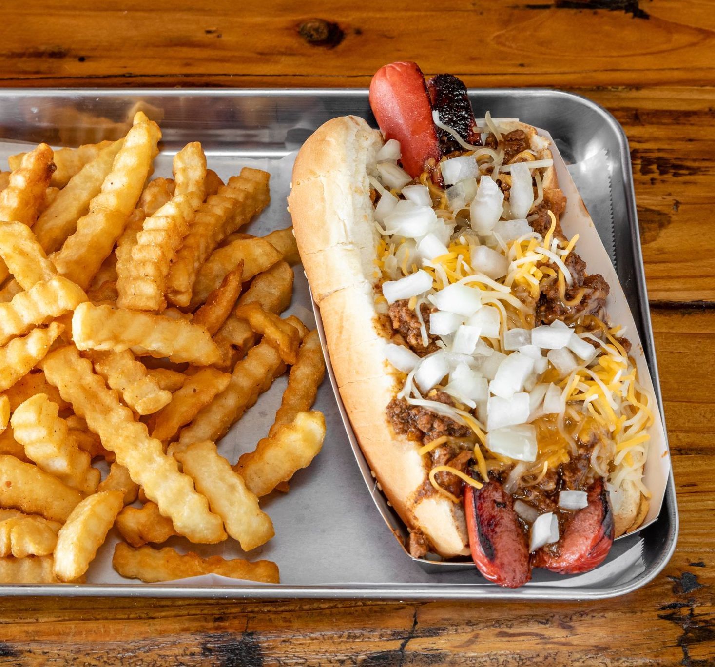 A chili dog and french fries on a metal tray
