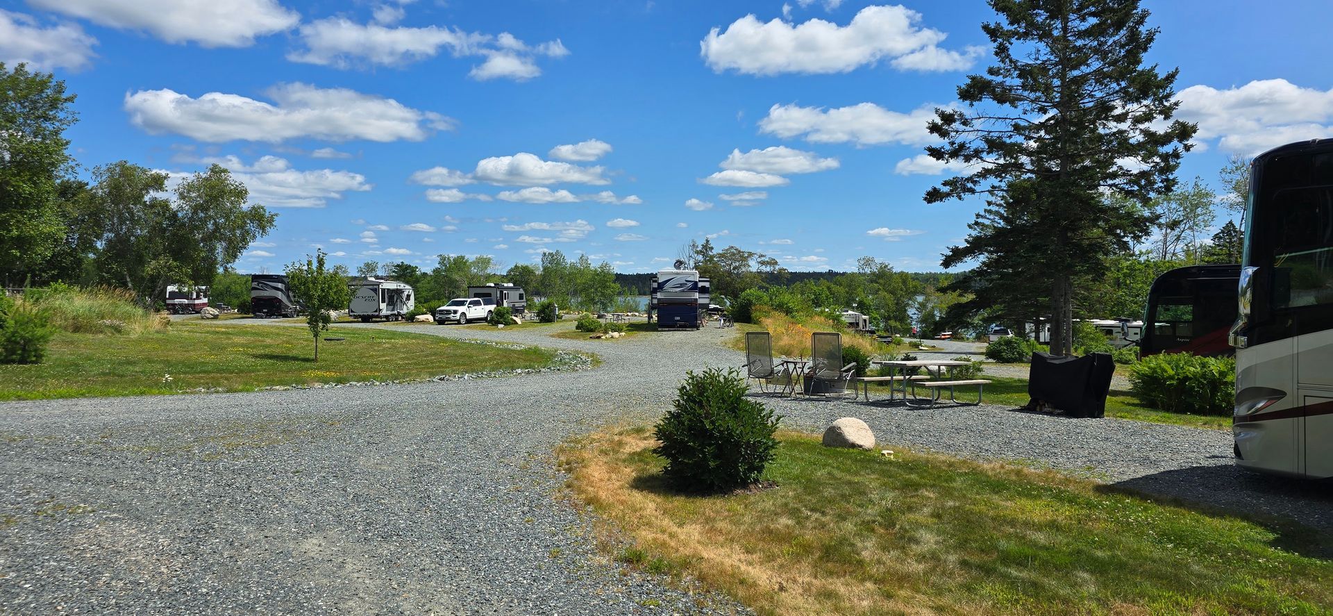 Rocky coastline with a narrow inlet of water between cliffs, trees on the cliff edges, and a bright blue sky.