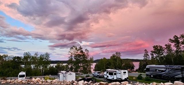 Vibrant sunset sky over a campground near a lake.