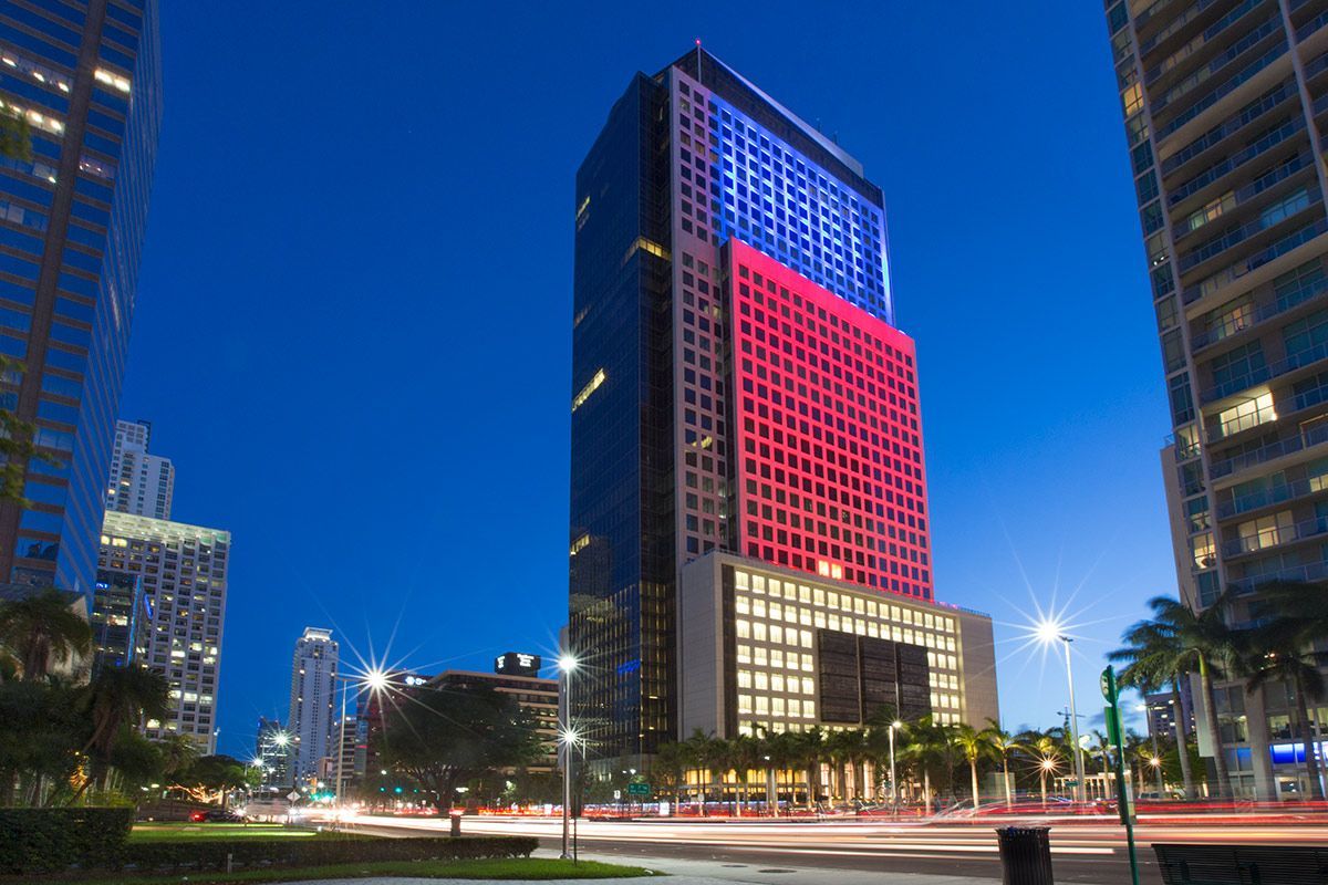 A person stands before a large mural featuring a person's face blended with mechanical gears in a gallery setting.