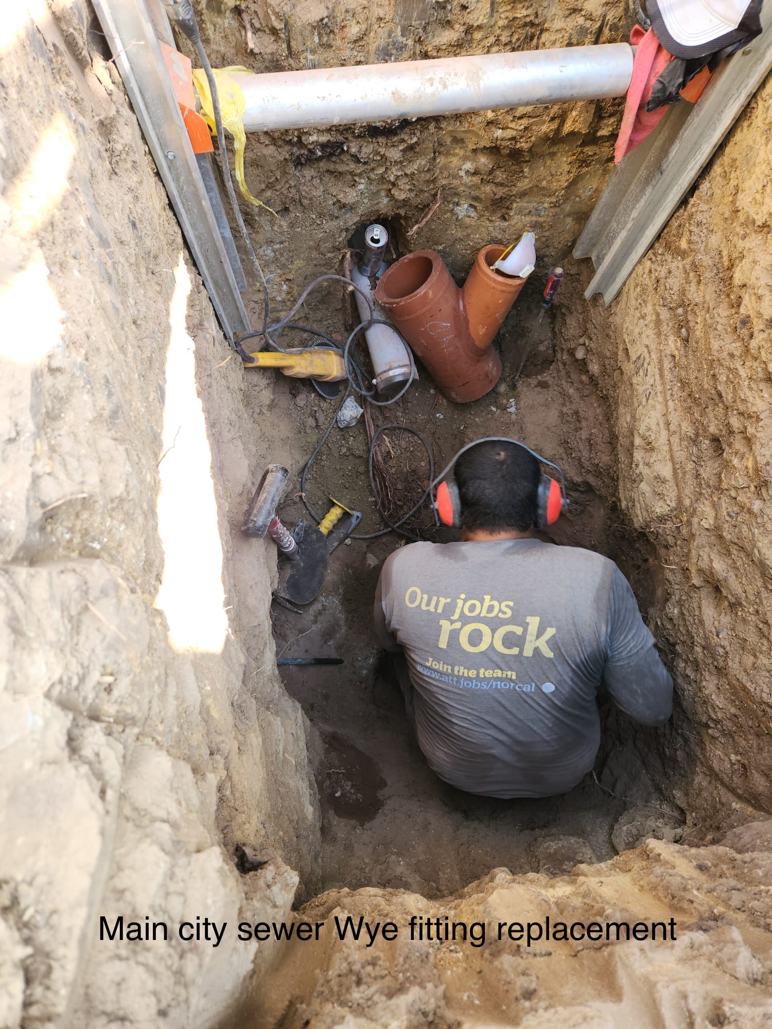 A man wearing headphones is sitting in a hole in the ground.