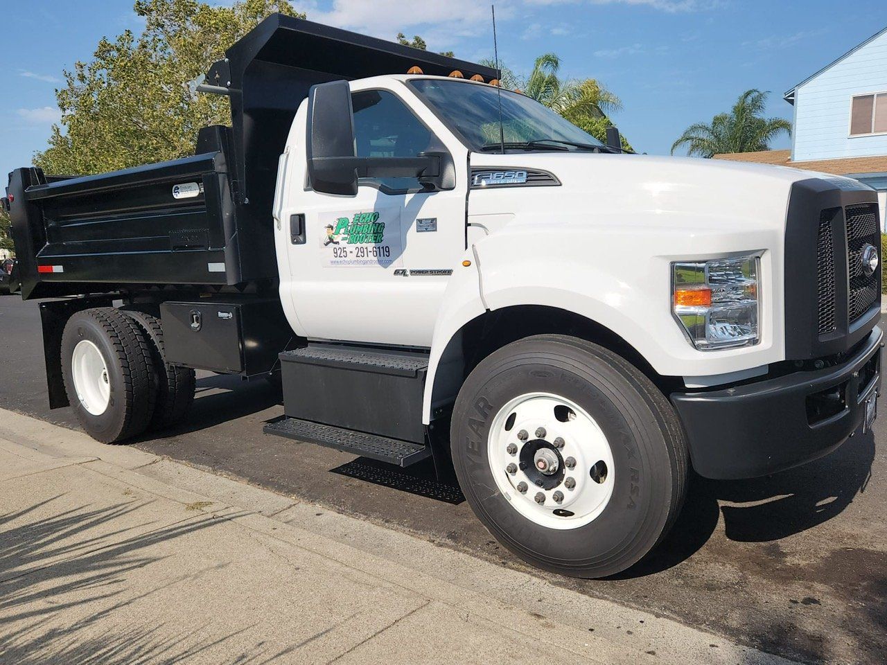A white dump truck is parked on the side of the road