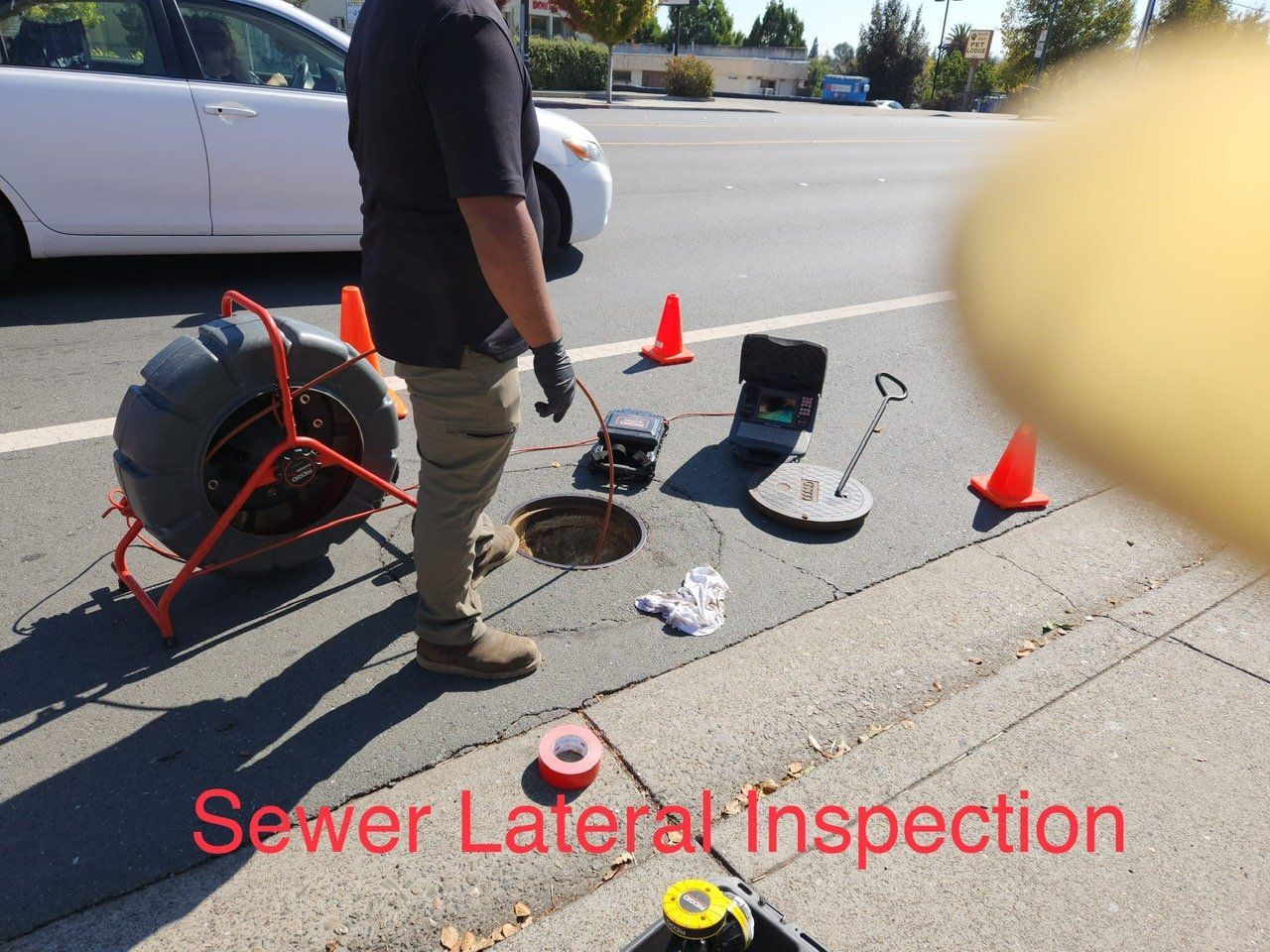 A man is doing a sewer lateral inspection on the sidewalk