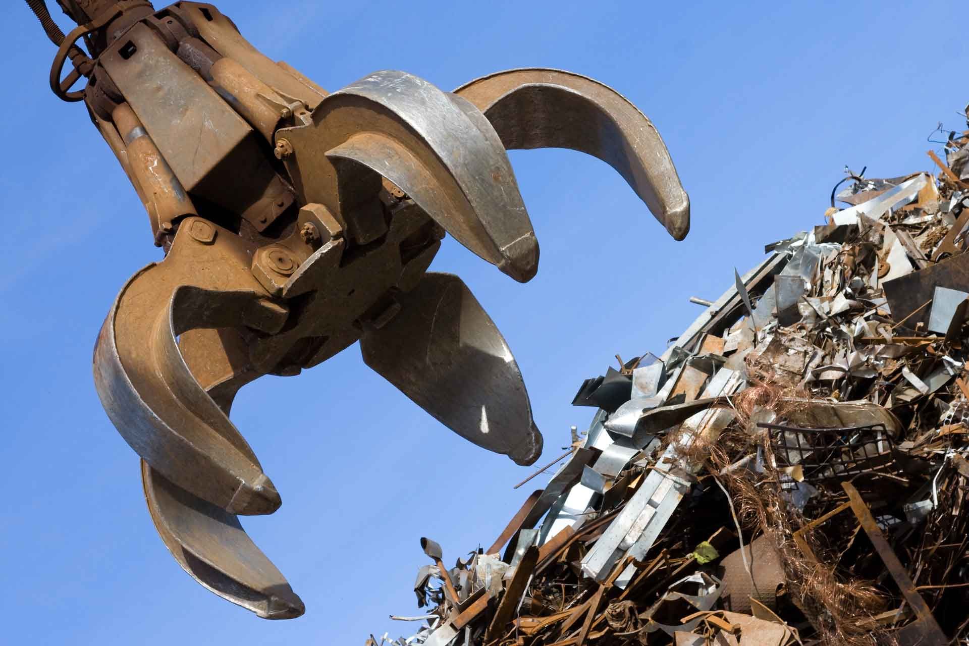 A large claw is reaching into a pile of scrap metal