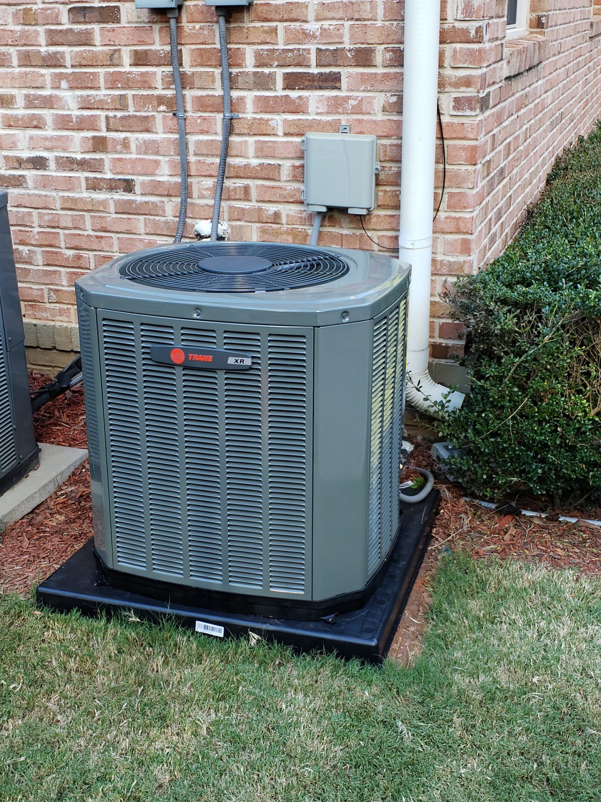 Two air conditioners are sitting outside of a brick building