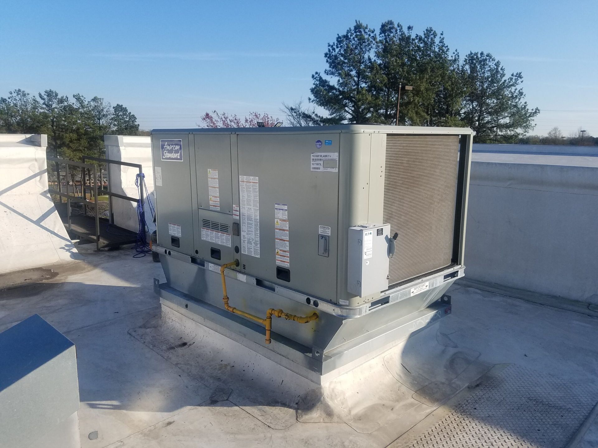 An air conditioner on top of a roof with trees in the background