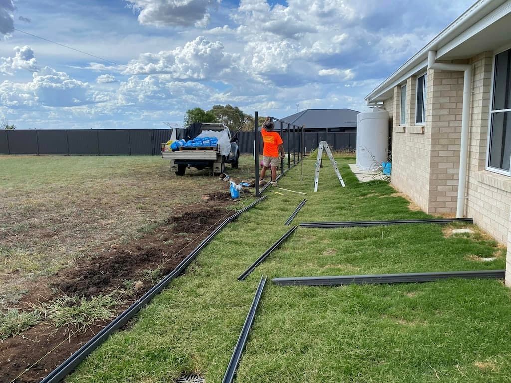 A Man Is Working on A Fence in Front of A House — DW Fencing Tamworth in Werris Creek, NSW
