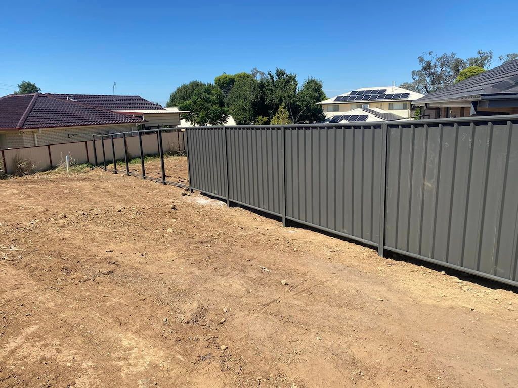 A Fence Surrounds a Dirt Field with A House in The Background — DW Fencing Tamworth in Taminda, NSW
