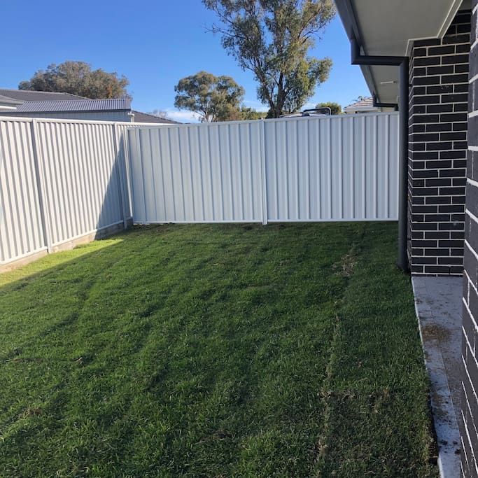A Backyard with A White Fence and A Lot of Grass — DW Fencing Tamworth in Taminda, NSW