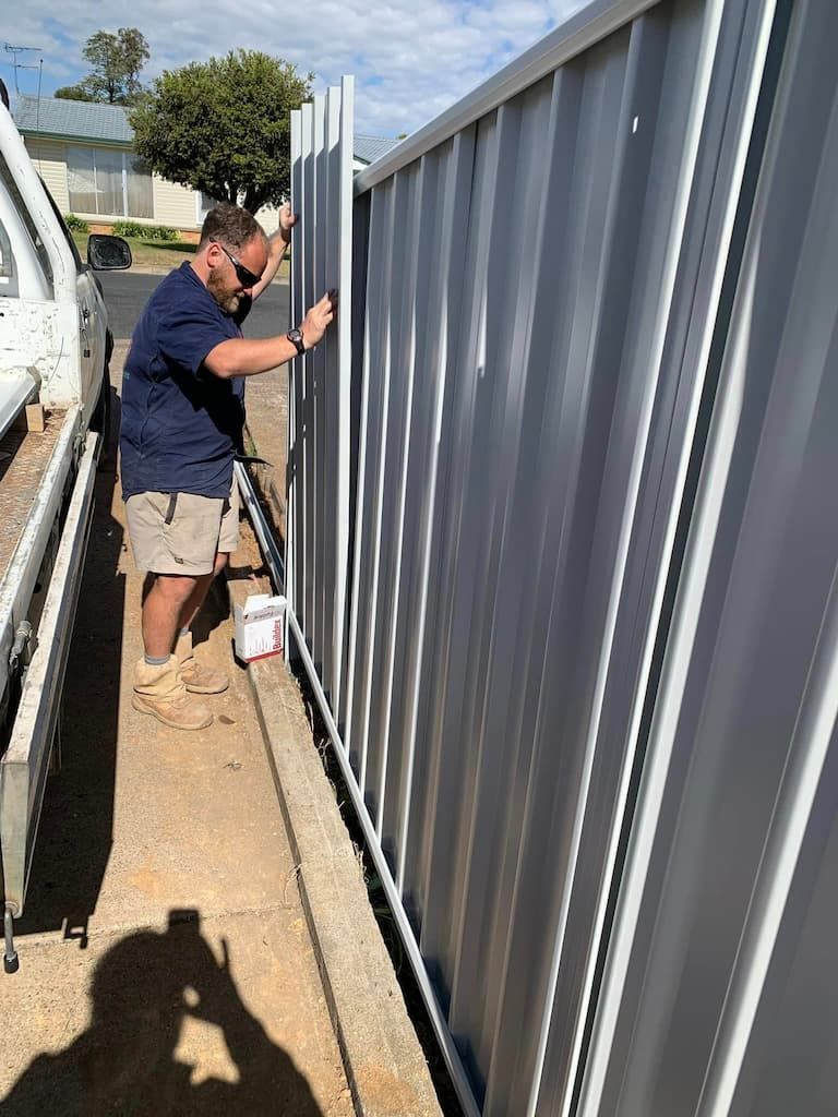 A Man Is Painting a Metal Fence with A Brush — DW Fencing Tamworth in Quirindi, NSW