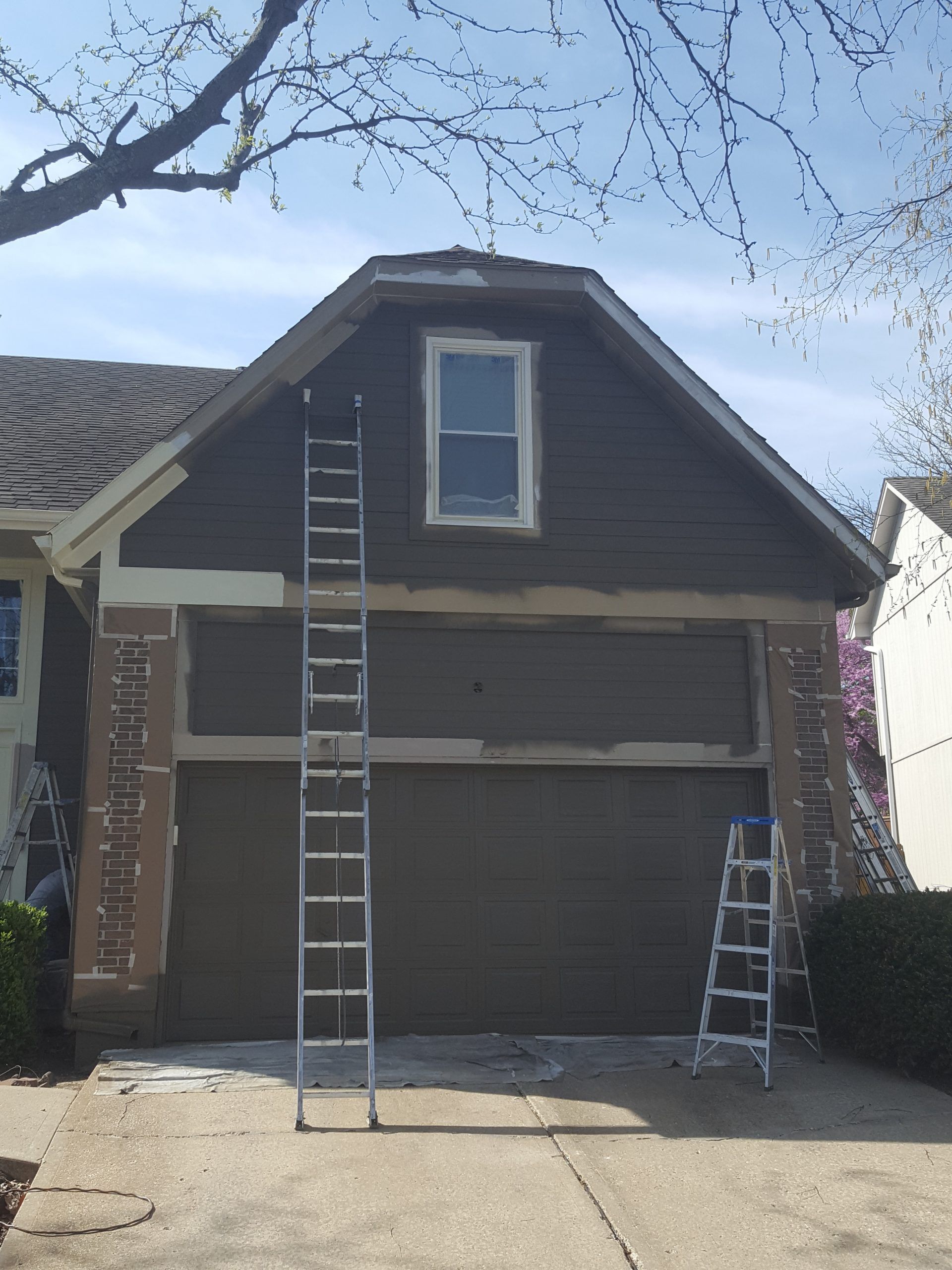 A house is being painted with a ladder hanging from the side of it